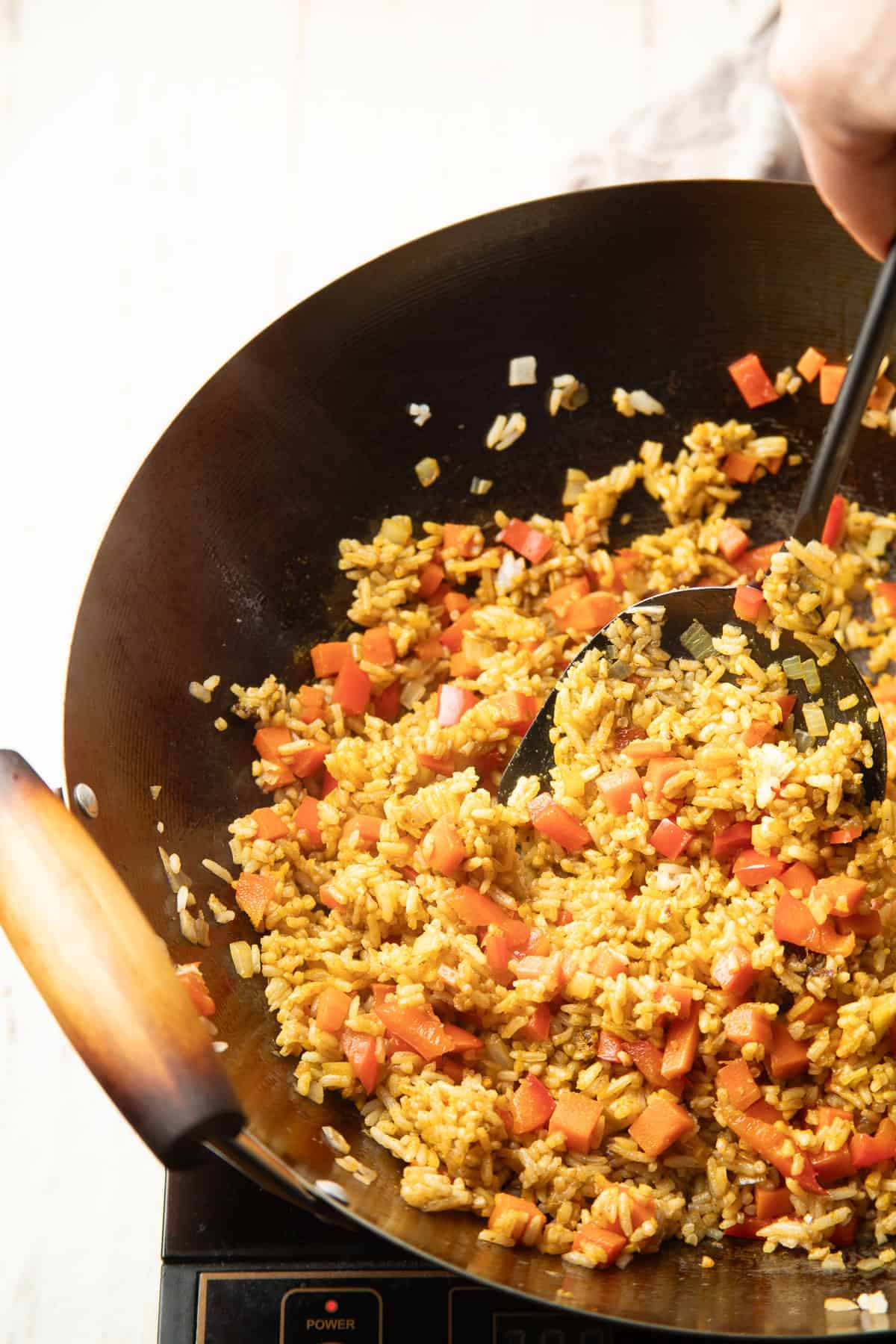 Curry fried rice stir-frying in a skillet.
