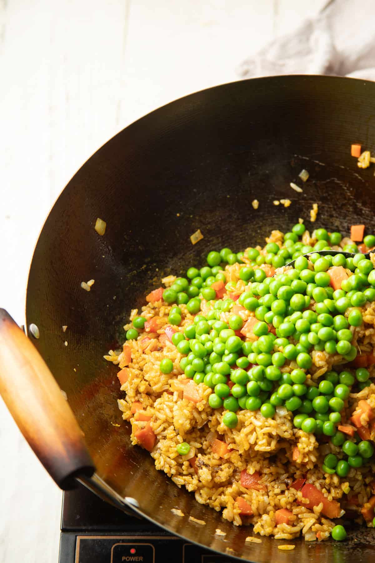 Curry Fried Rice cooking in a wok after adding peas.