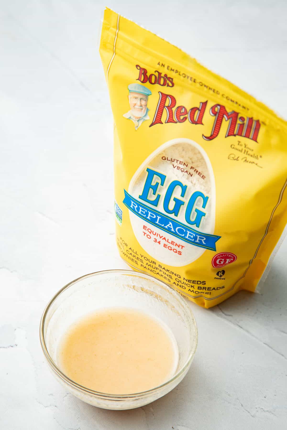 Bag of Bob's Red Mill egg replacer and a small bowl of egg replacer mixed with water.