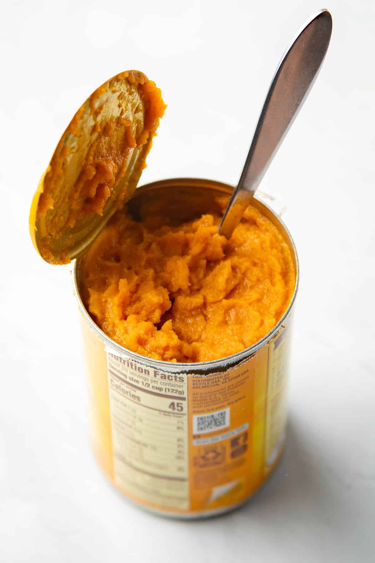 Open can of pumpkin puree with a spoon in it.