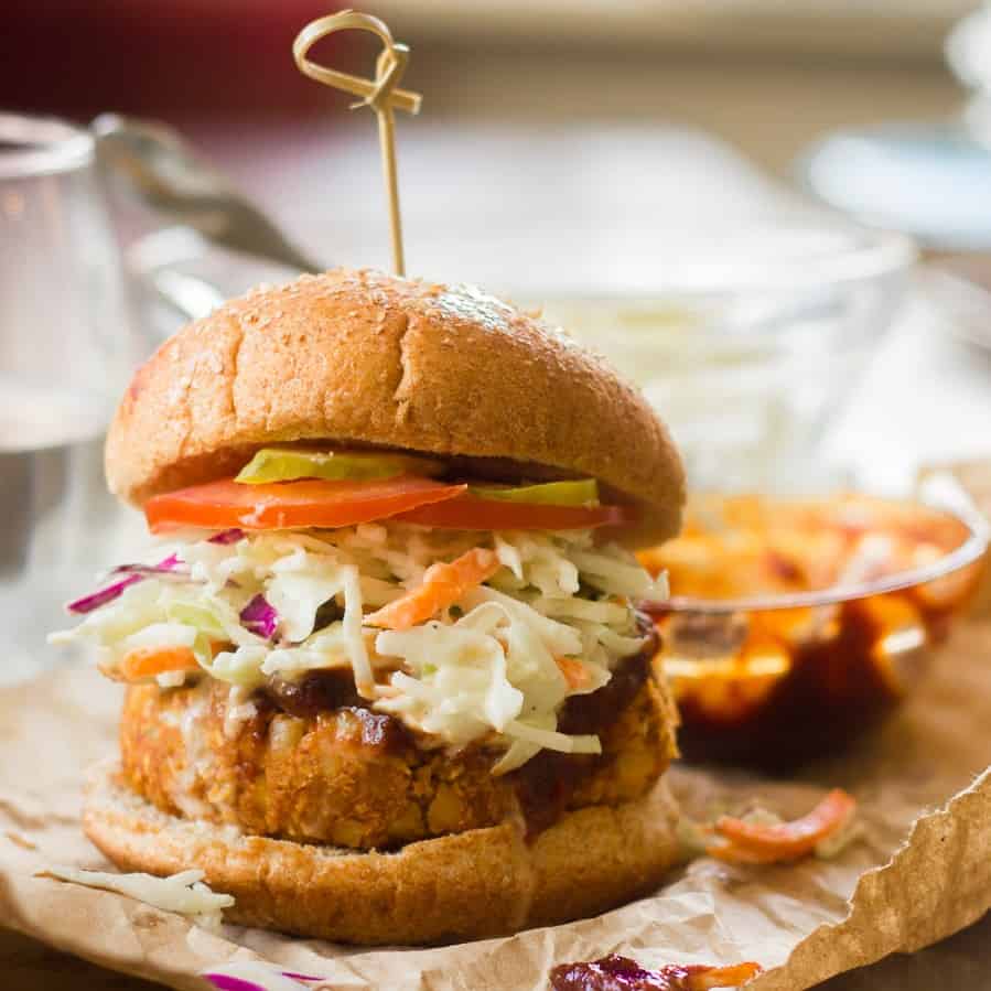 Barbecue chickpea burger topped with coleslaw, tomato and pickle slices.