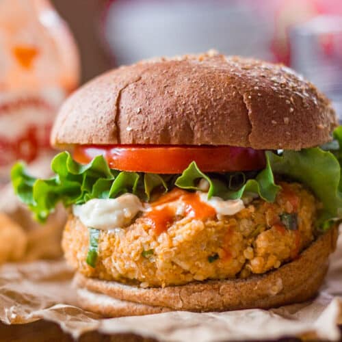 Close up of a Buffalo chickpea quinoa burger with lettuce, tomato, and mayo on top.
