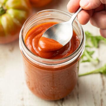 Hand scooping Vegan French Dressing from a jar with a spoon.