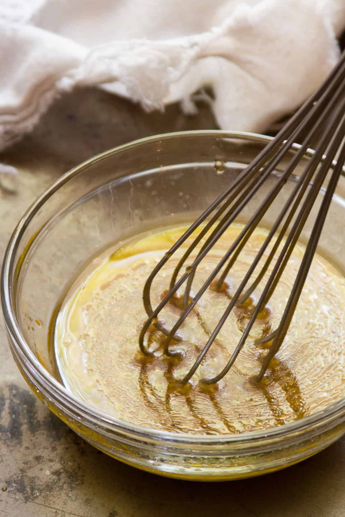 Maple dijon sauce being whisked in a bowl.