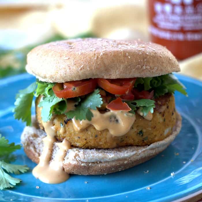 Sweet potato falafel burger on a plate with tahini dripping from the patty.