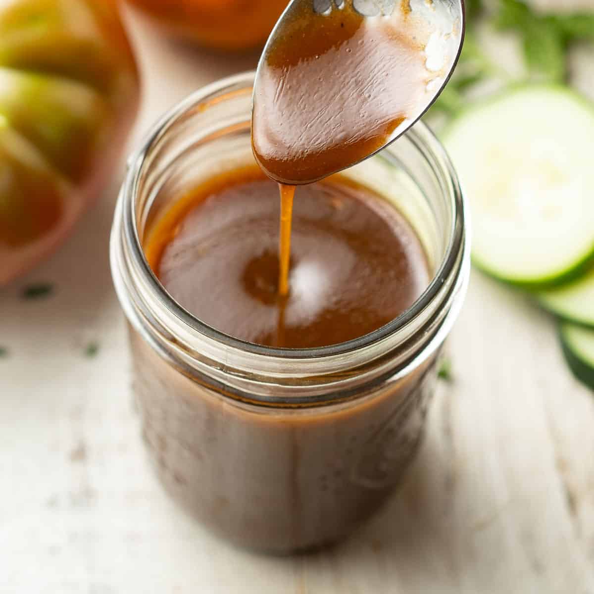 Maple Balsamic Vinaigrette being drizzled from a spoon into a jar.