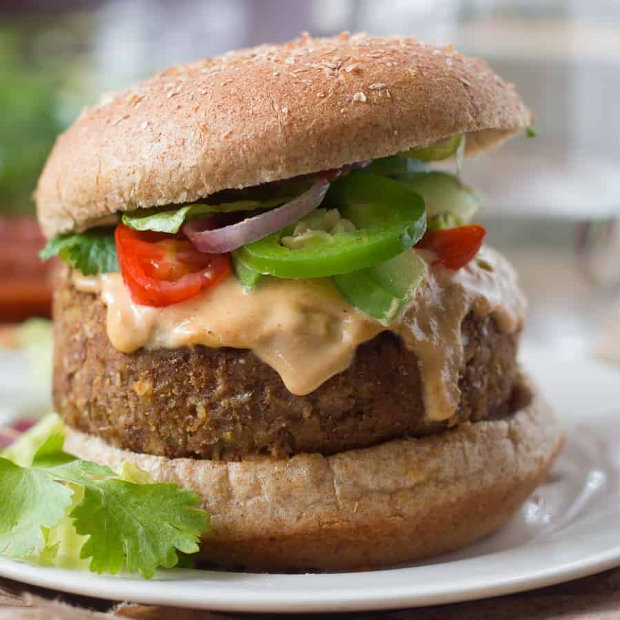 Vegan nacho burger dripping with sauce on a plate.