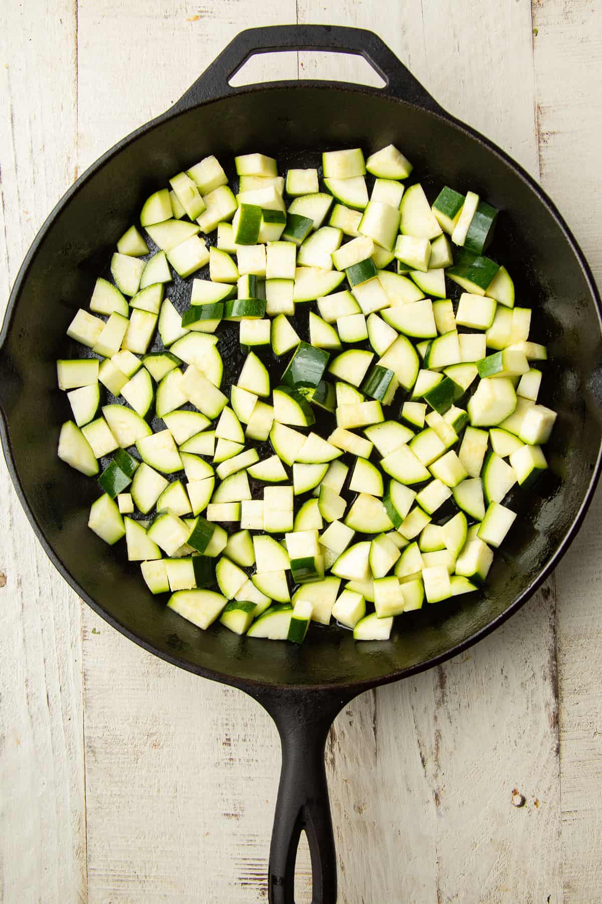 Skillet filled with chopped zucchini.