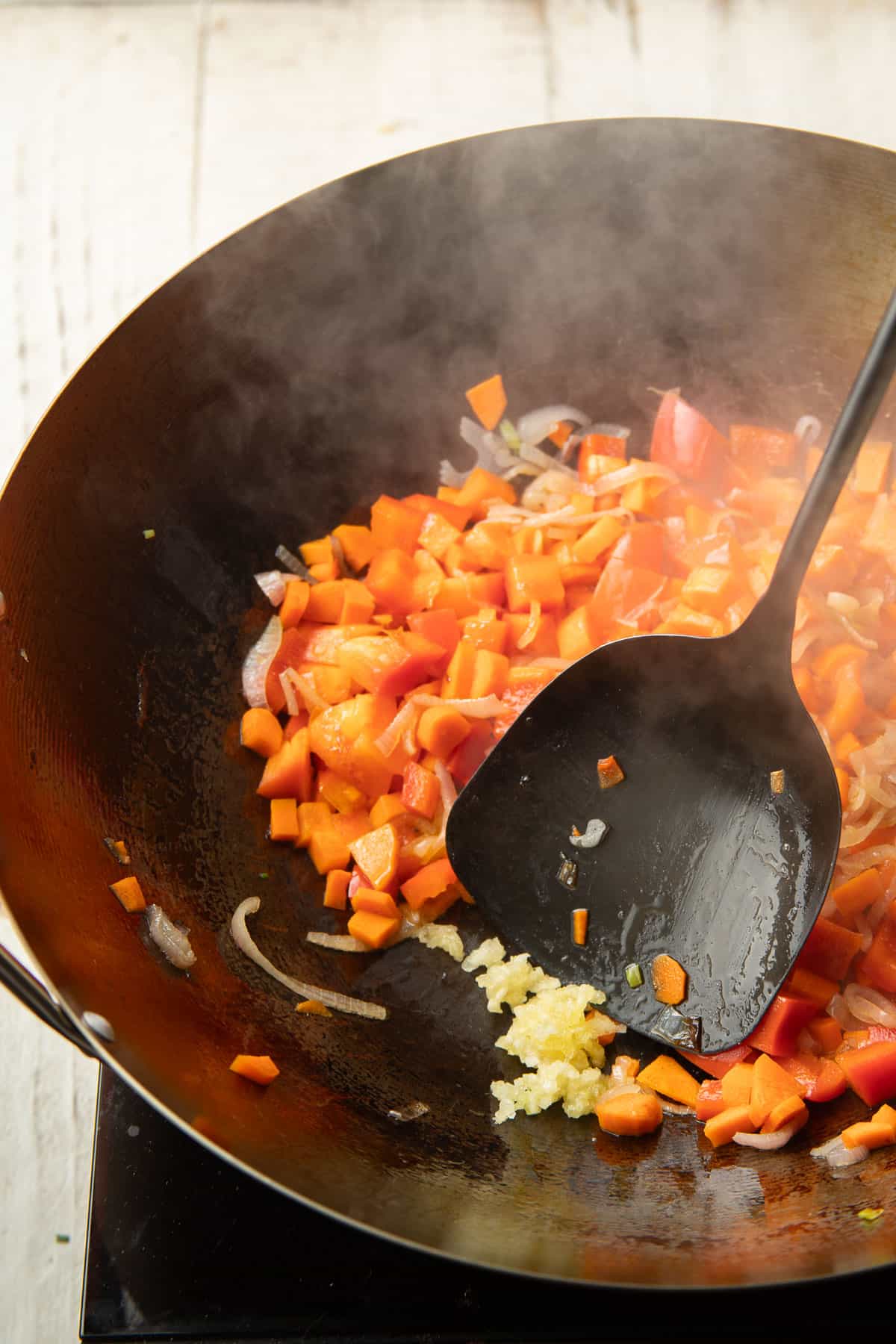 Minced cooking in a wok with stir-fried peppers and carrots.