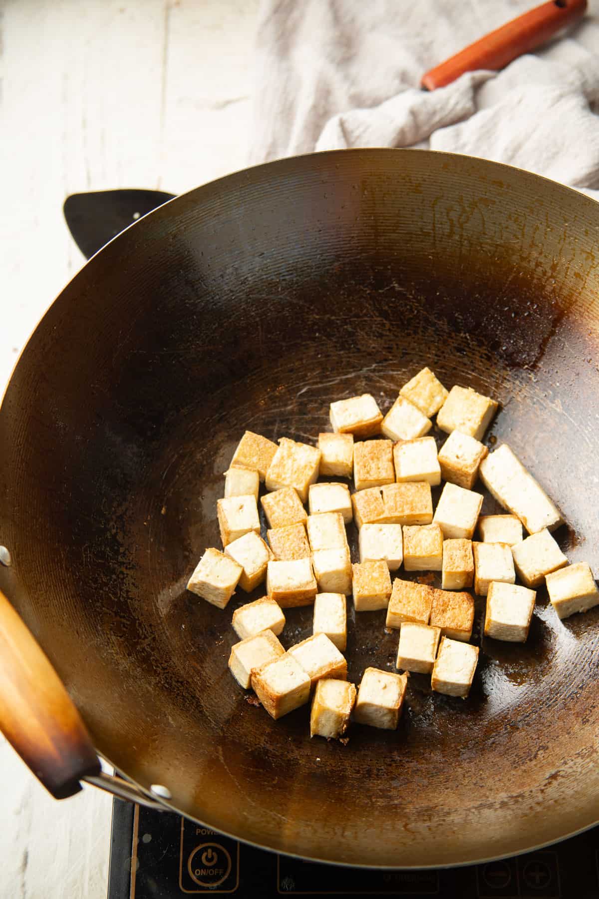 Tofu cubes cooking in a wok.