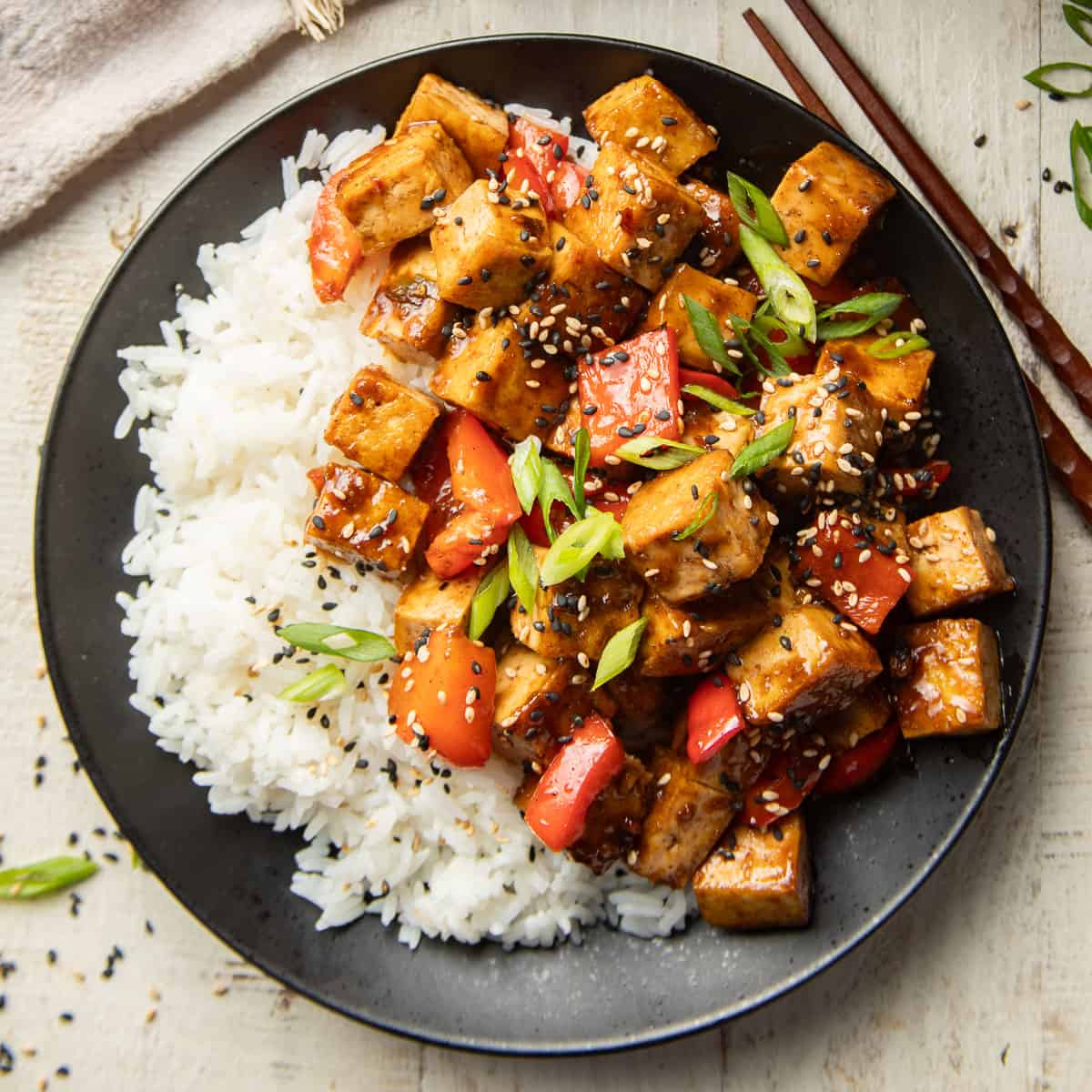 Plate of Szechuan Tofu and rice with chopsticks on the side.