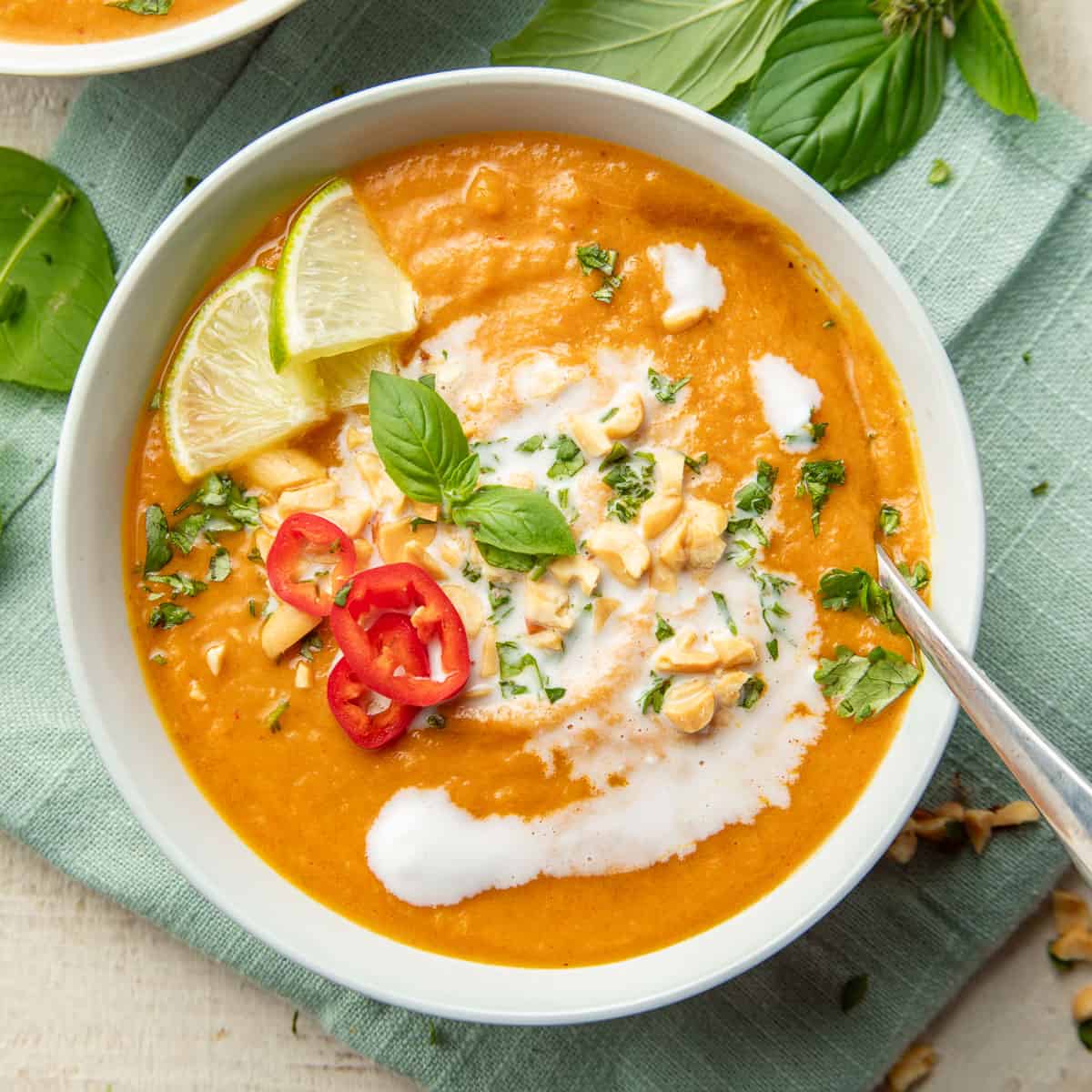 Bowl of Thai Pumpkin Soup topped with coconut milk, peanuts, and herbs.