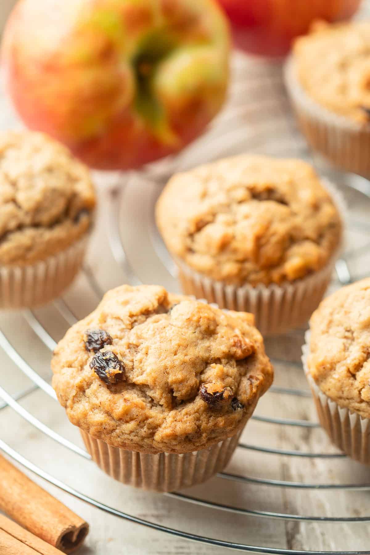 Vegan Applesauce Muffins on a cooling rack with an apple.