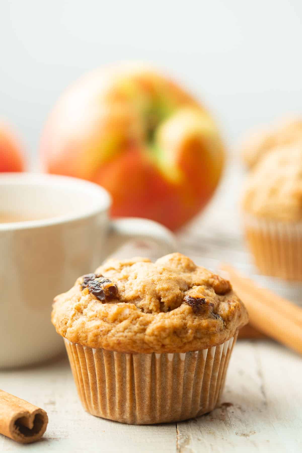 Vegan Applesauce Muffin with tea cup and apples in the background.