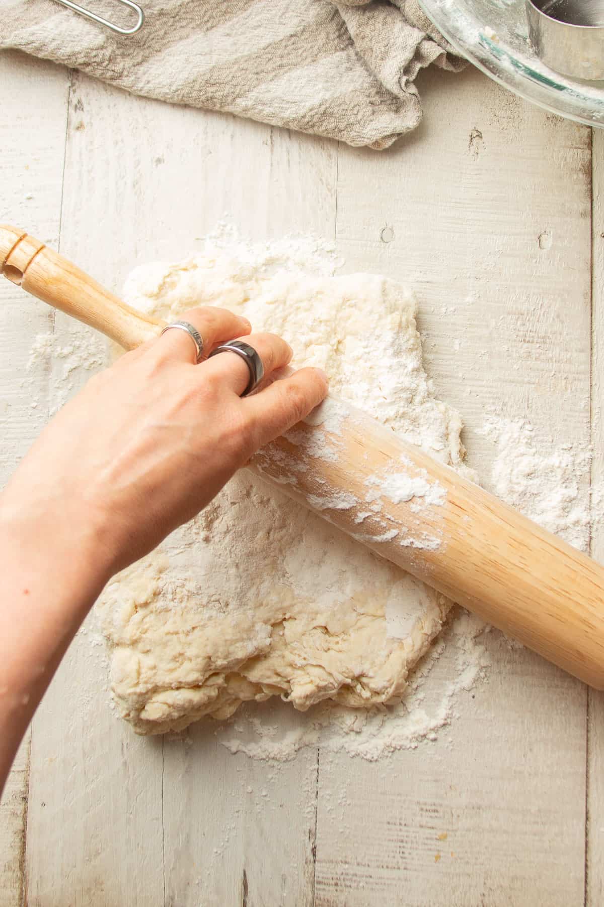 Hand rolling biscuit dough with a rolling pin.