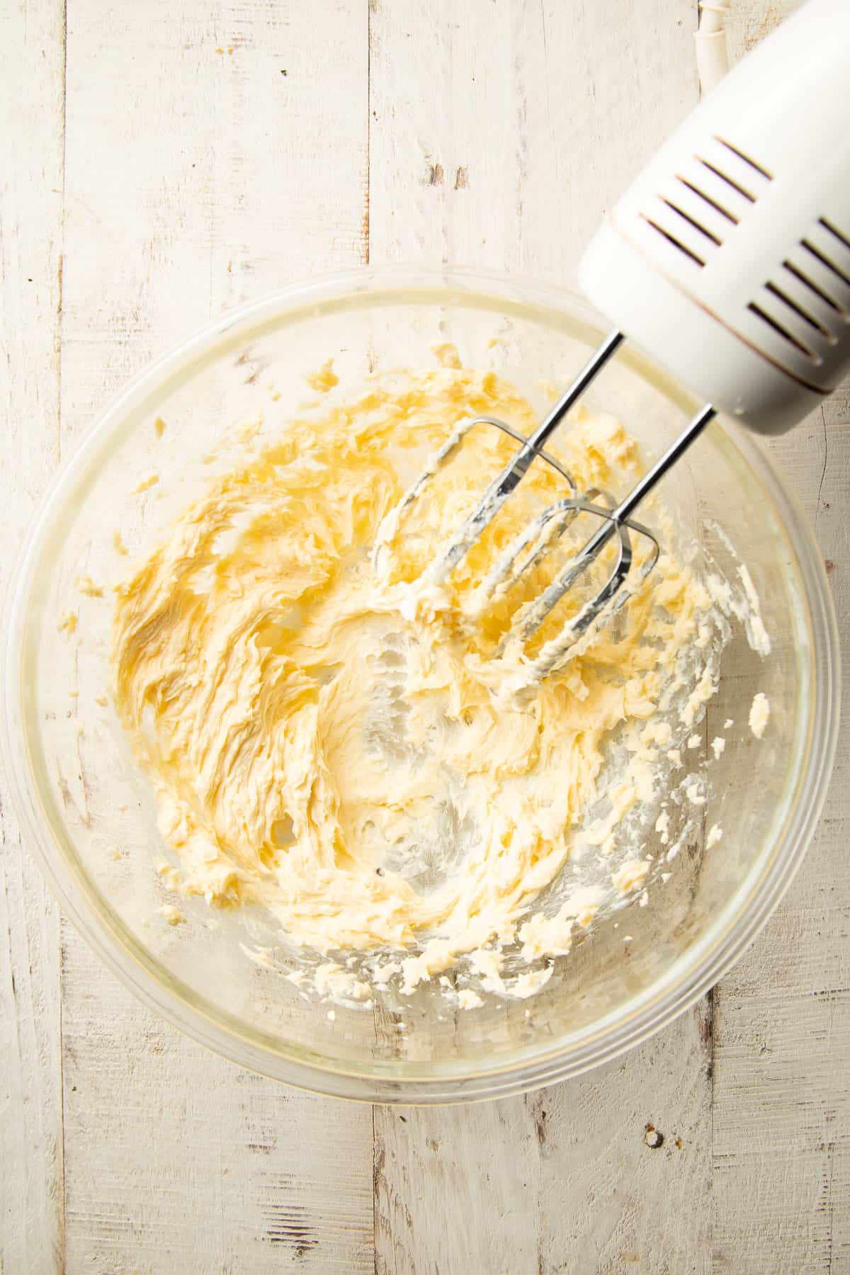 Creamed vegan butter in a mixing bowl with an electric mixer.