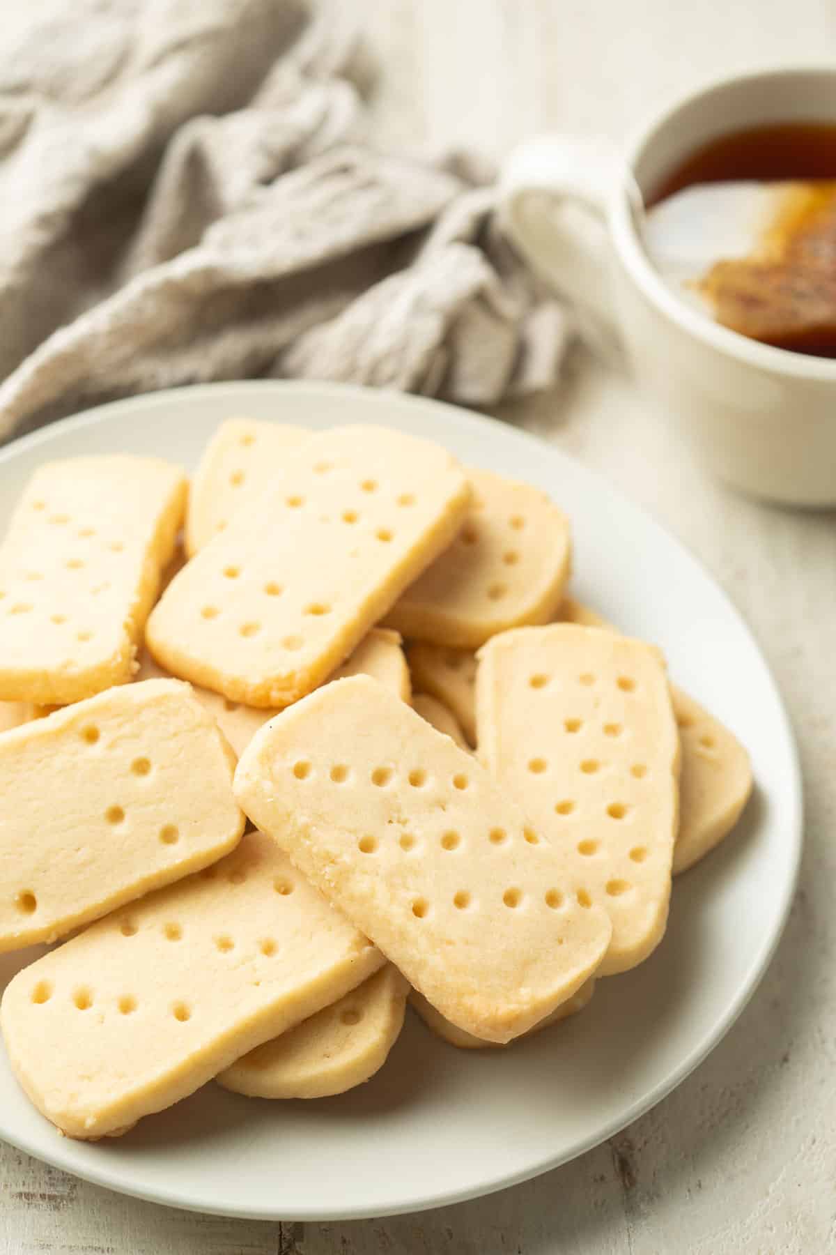 Plate of Vegan Shortbread Cookies with a cup of tea in the background.