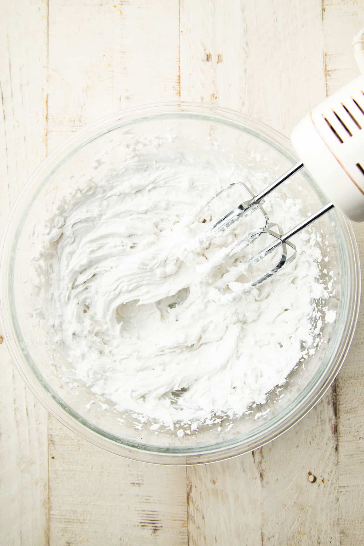 Whipped coconut cream in a bowl with electric mixer.