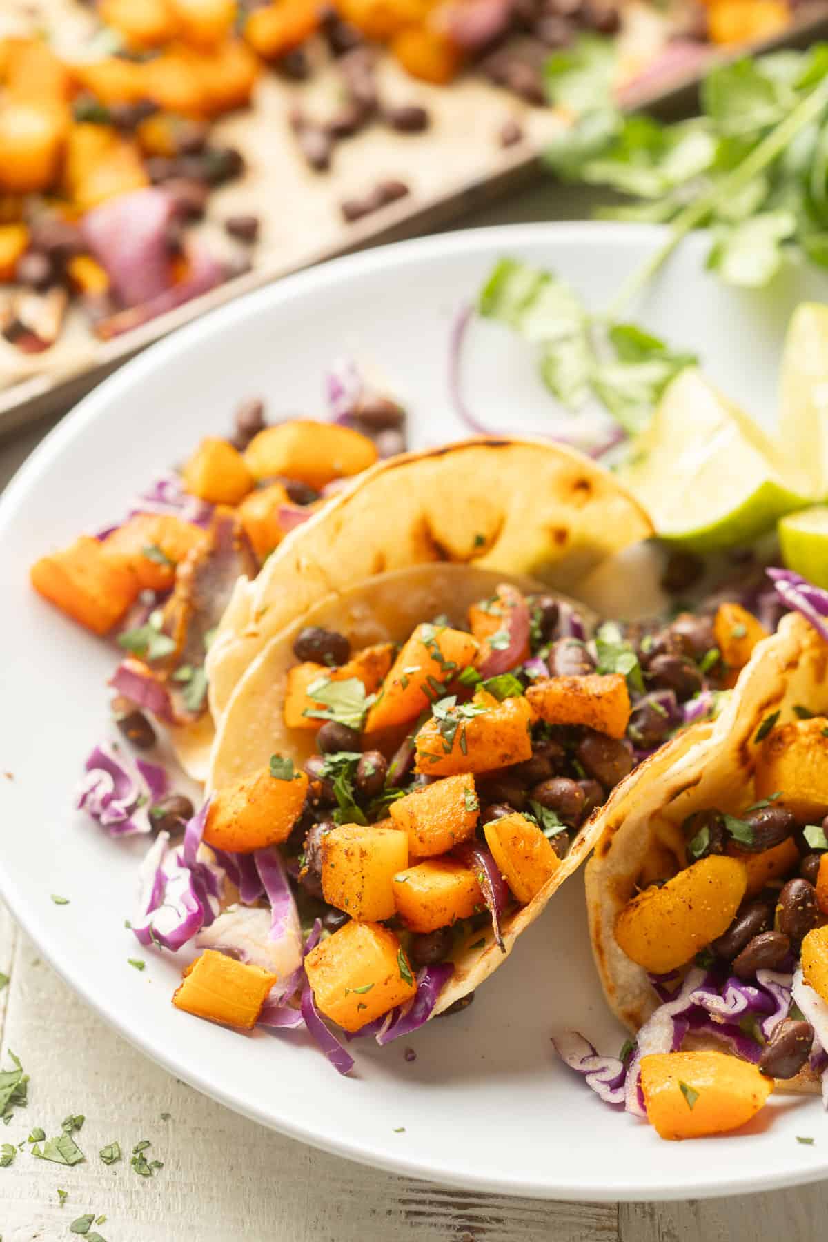 Butternut Squash Tacos on a dish with a baking sheet in the background.