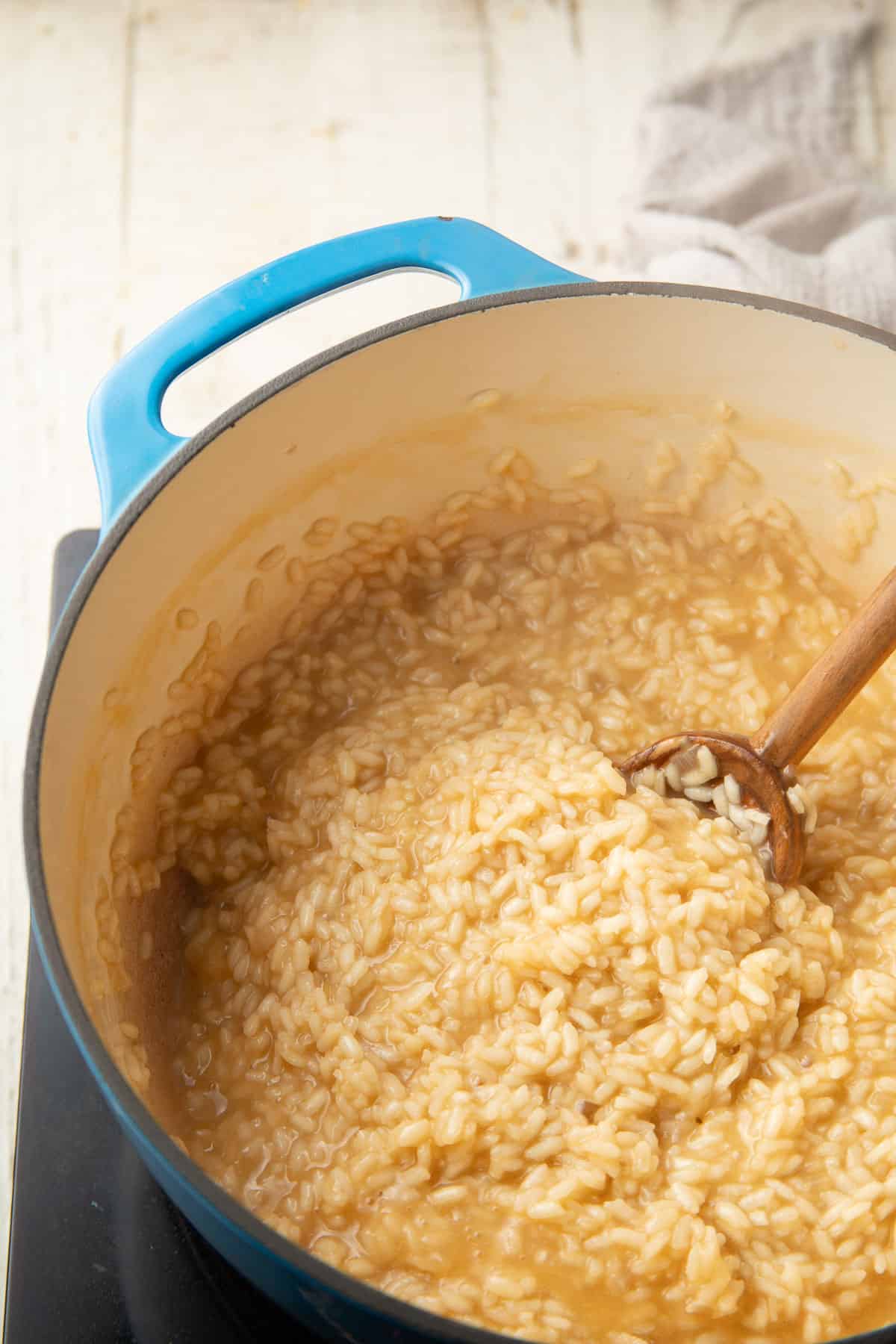 Risotto cooking in a pot with wooden spoon.