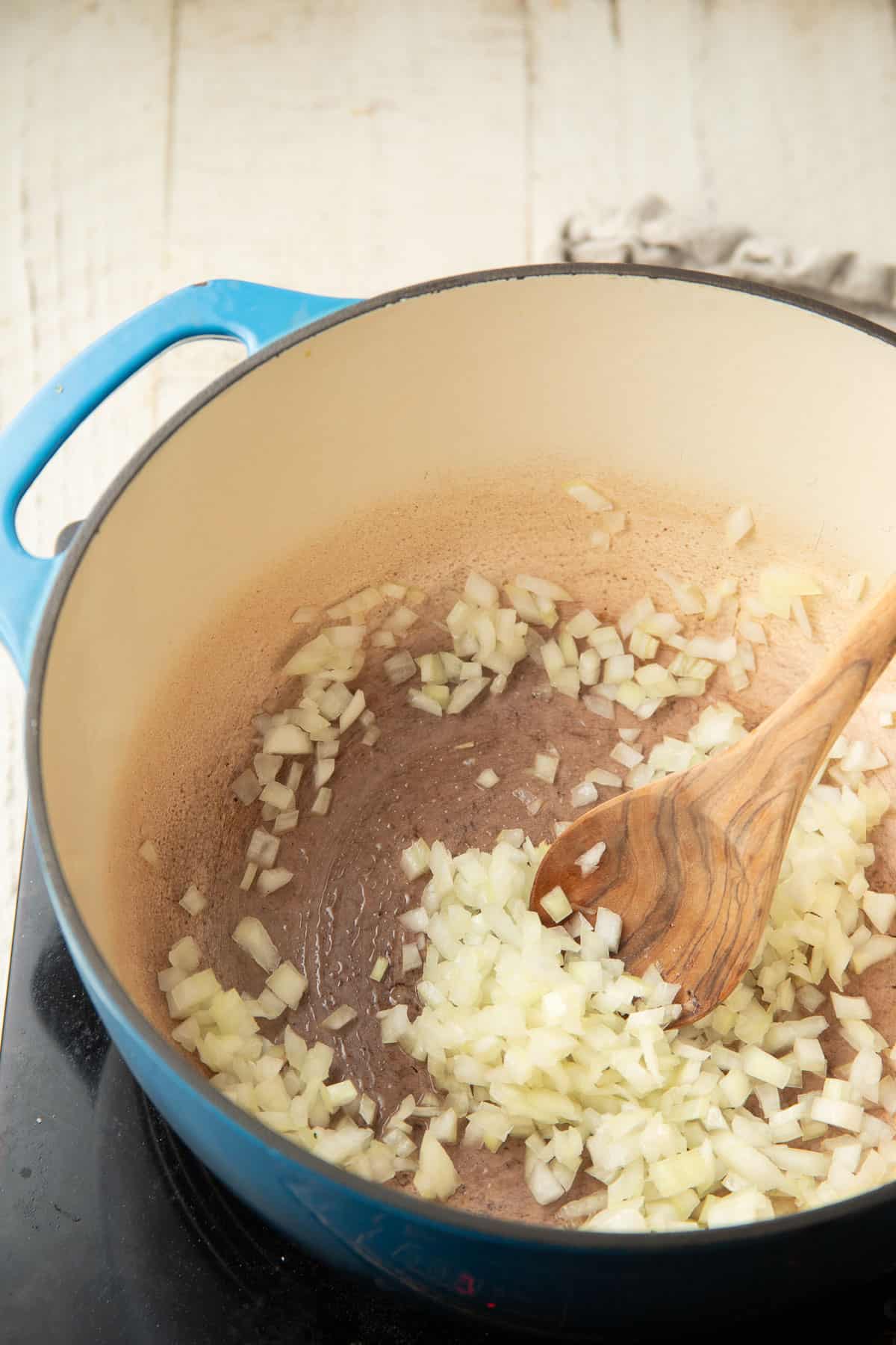 Diced onion cooking in a pot with spoon.