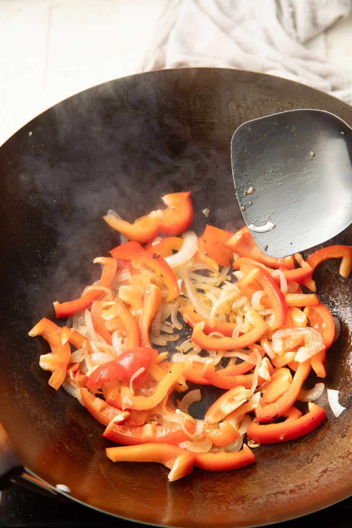 Peppers and onions stir-frying in a wok.