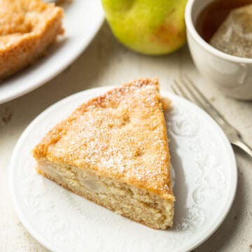 Slice of Vegan Pear Cake on a dish with powdered sugar on top.