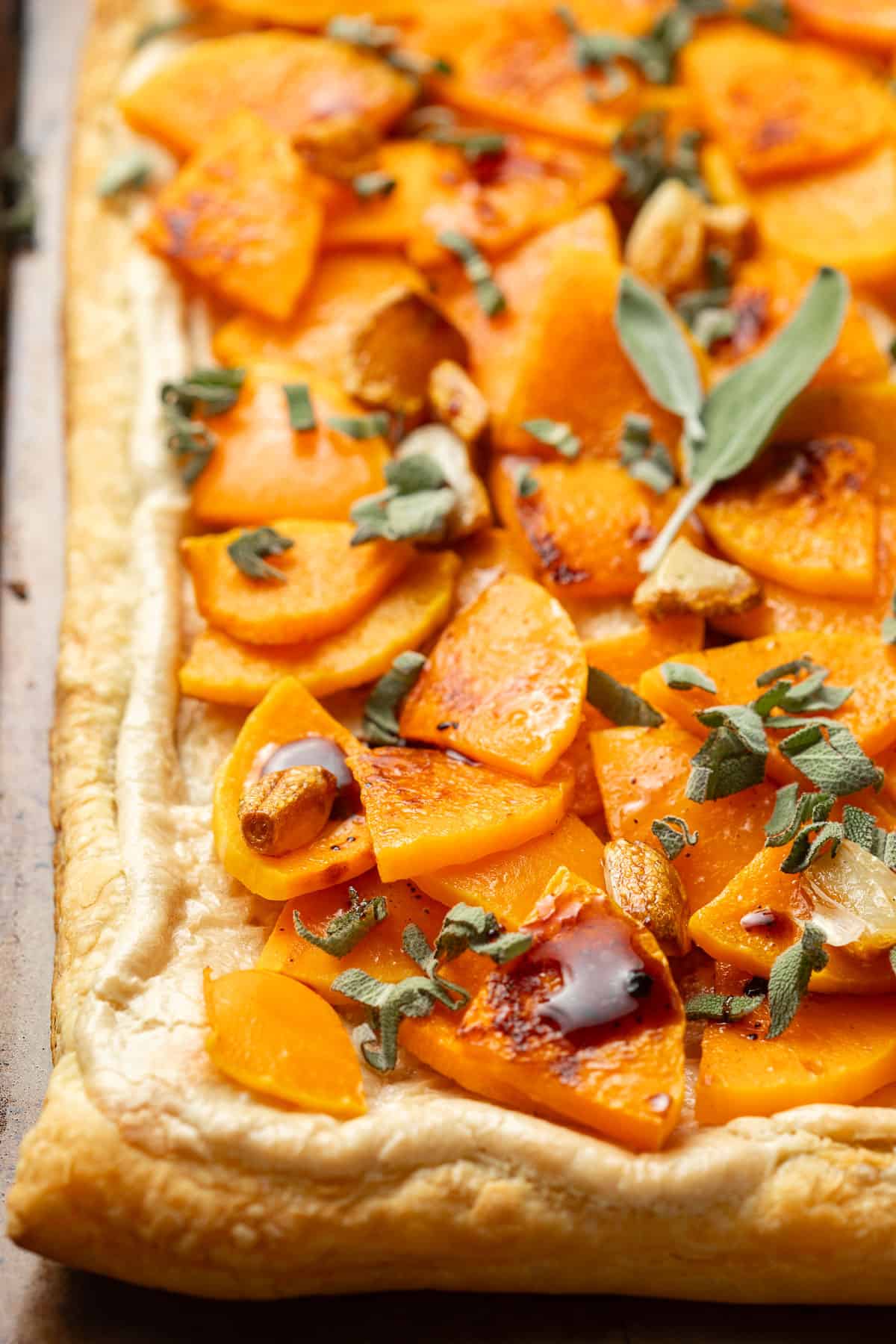 Corner of a Butternut Squash Tart topped with roasted garlic, sage and balsamic vinegar.