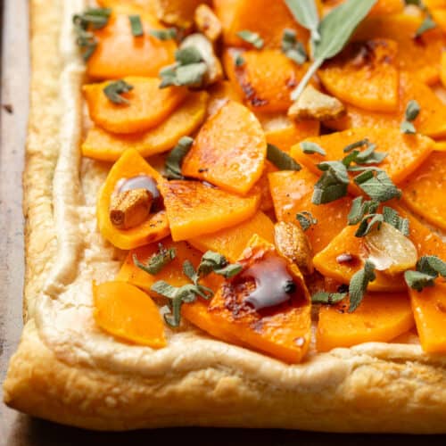 Corner of a Butternut Squash Tart topped with sage, roasted garlic and balsamic vinegar.