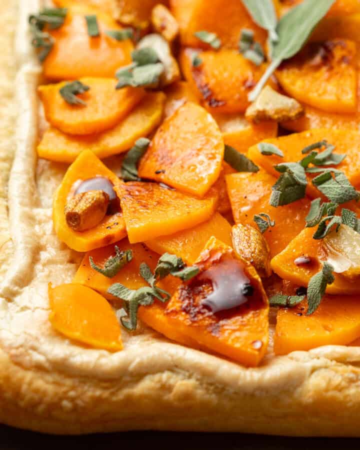Corner of a Butternut Squash Tart topped with sage, roasted garlic and balsamic vinegar.