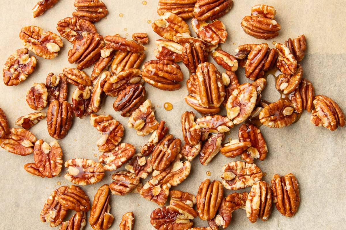Maple syrup soaked pecans on parchment paper.
