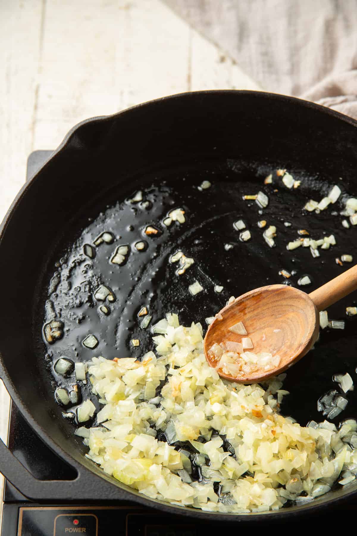 Diced onion cooking in oil in a skillet.