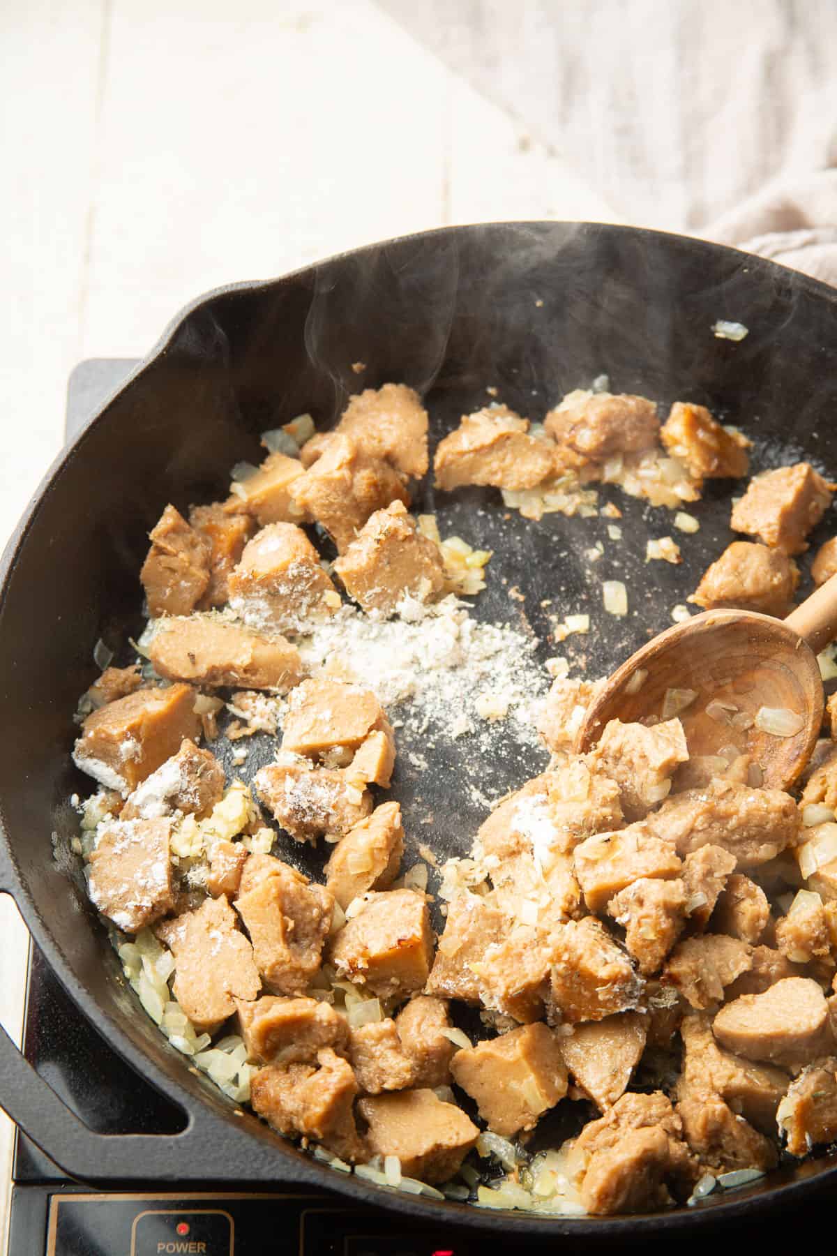Seitan, onions, garlic and flour cooking in a skillet.