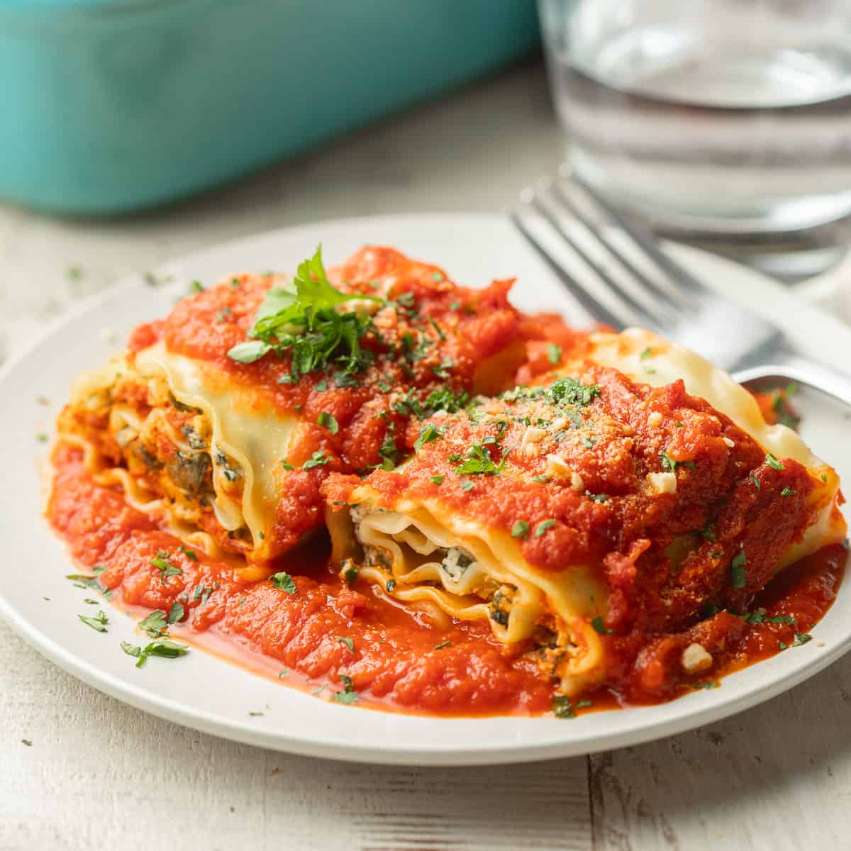 Two Vegan Lasagna Roll-Ups on a plate with fresh parsley on top.