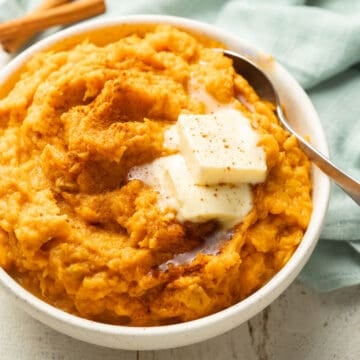 Bowl of Vegan Mashed Sweet Potatoes topped with butter and cinnamon.