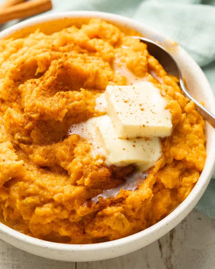 Bowl of Vegan Mashed Sweet Potatoes topped with butter and cinnamon.