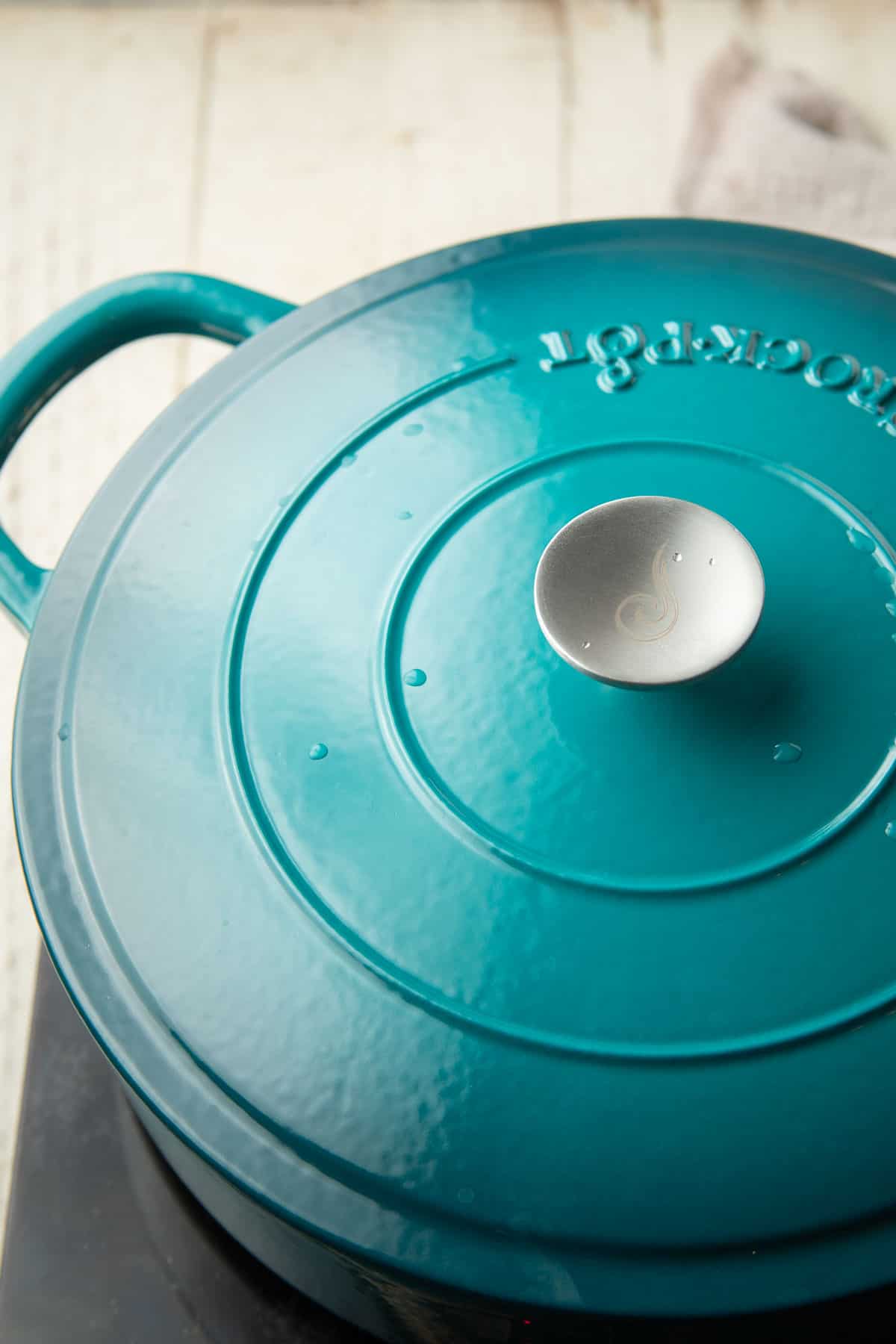 Blue pot with a lid on top sitting on a cooking surface.