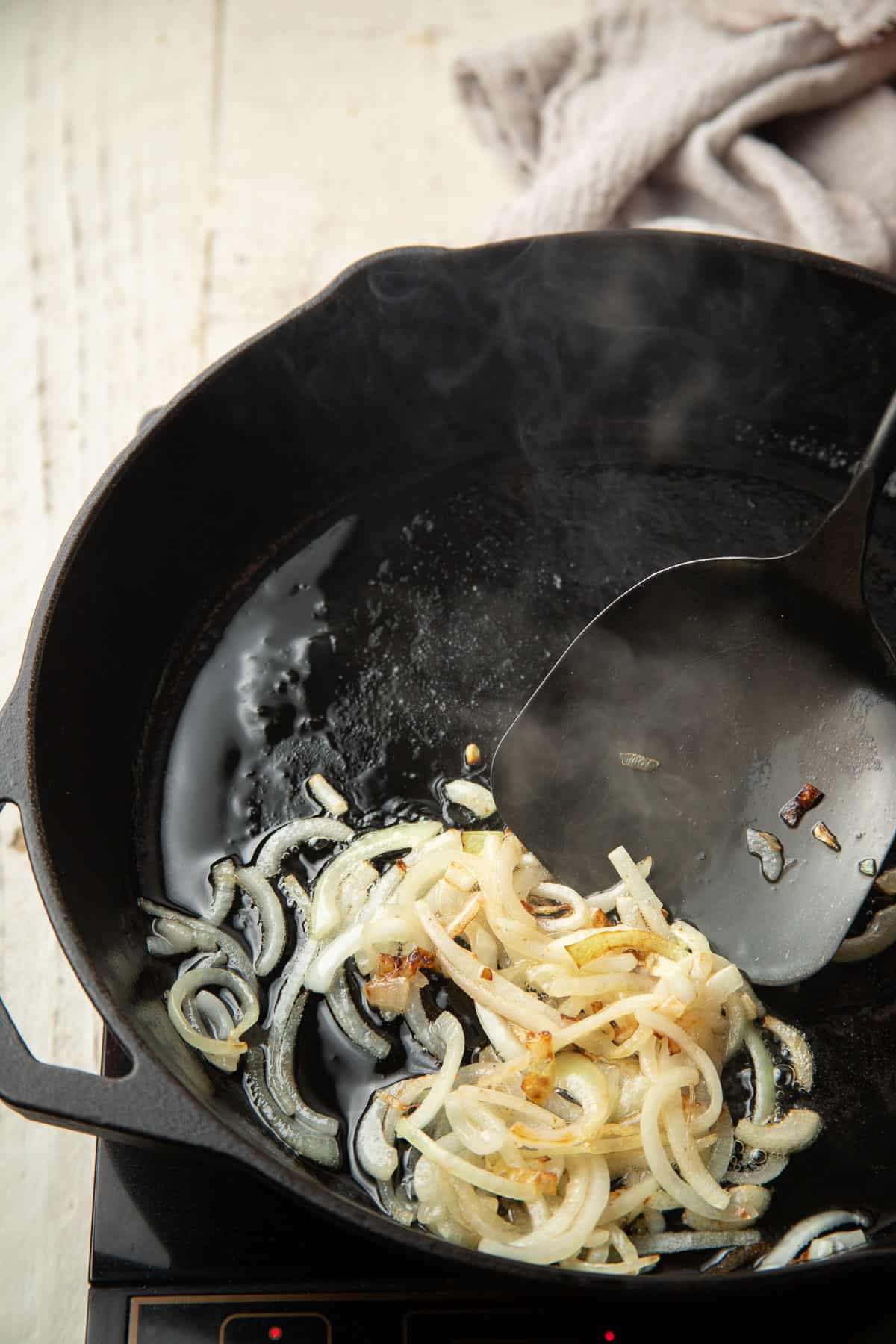 Onions cooking in oil in a skillet.