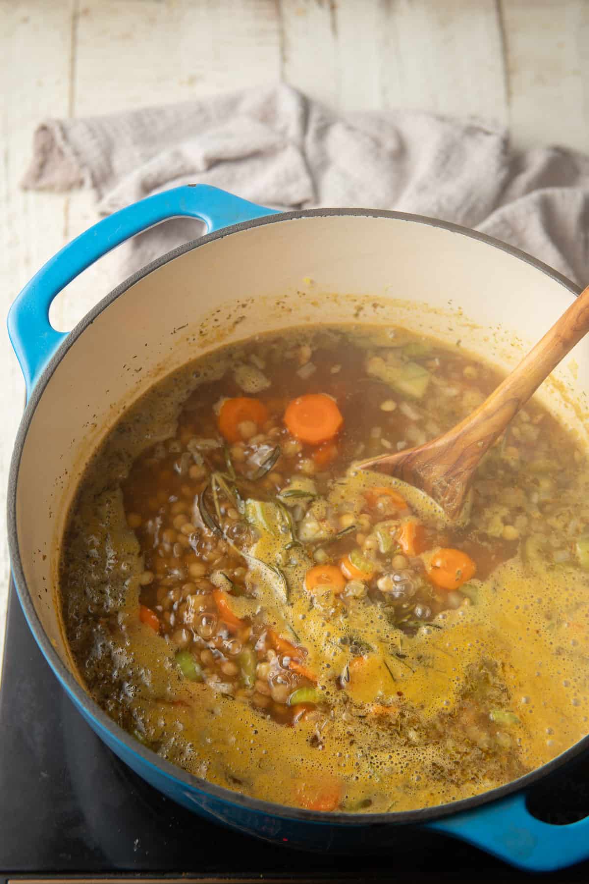 Lentil soup simmering with a wooden spoon.