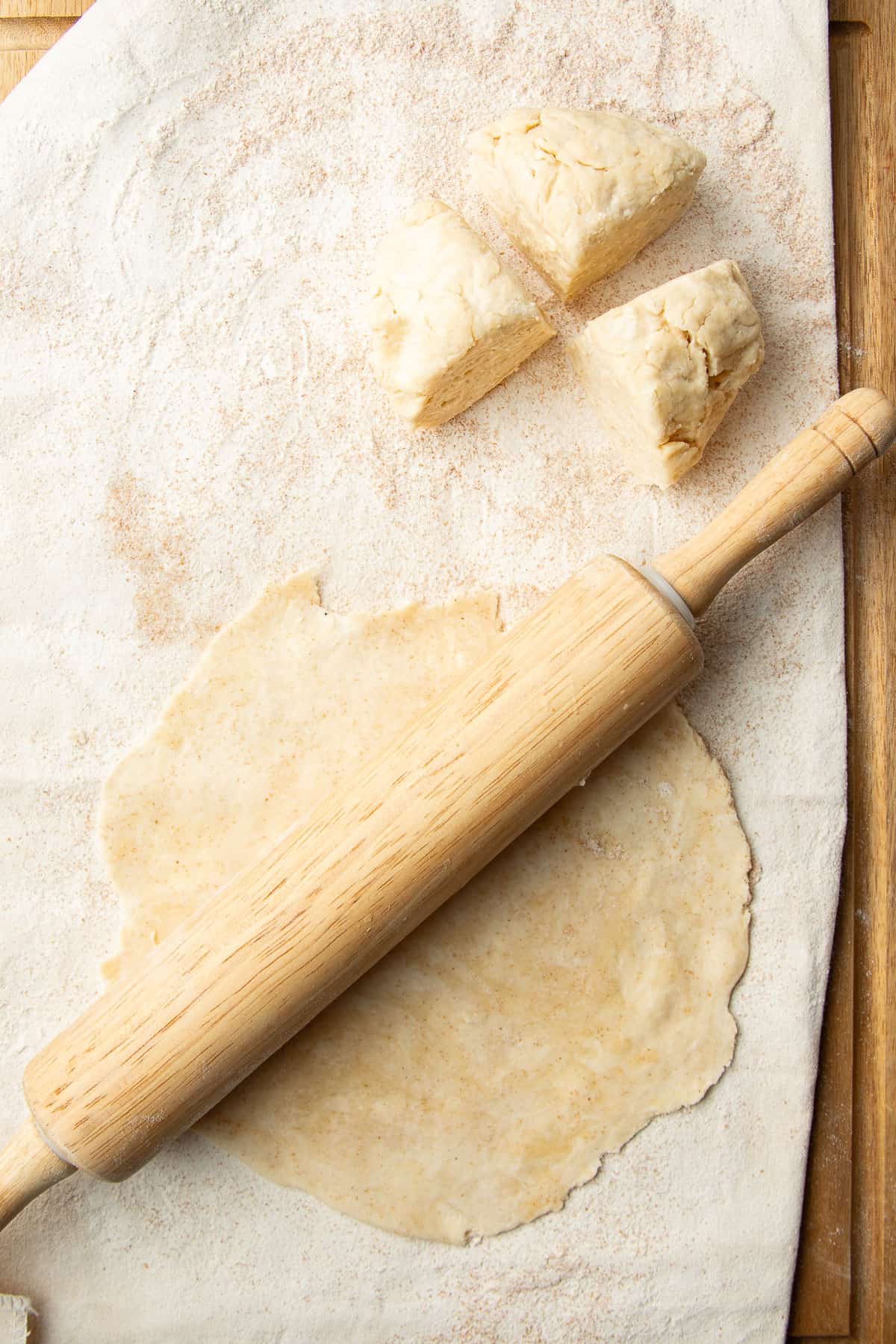 Rolling pin on top of a circle of rolled pastry dough.