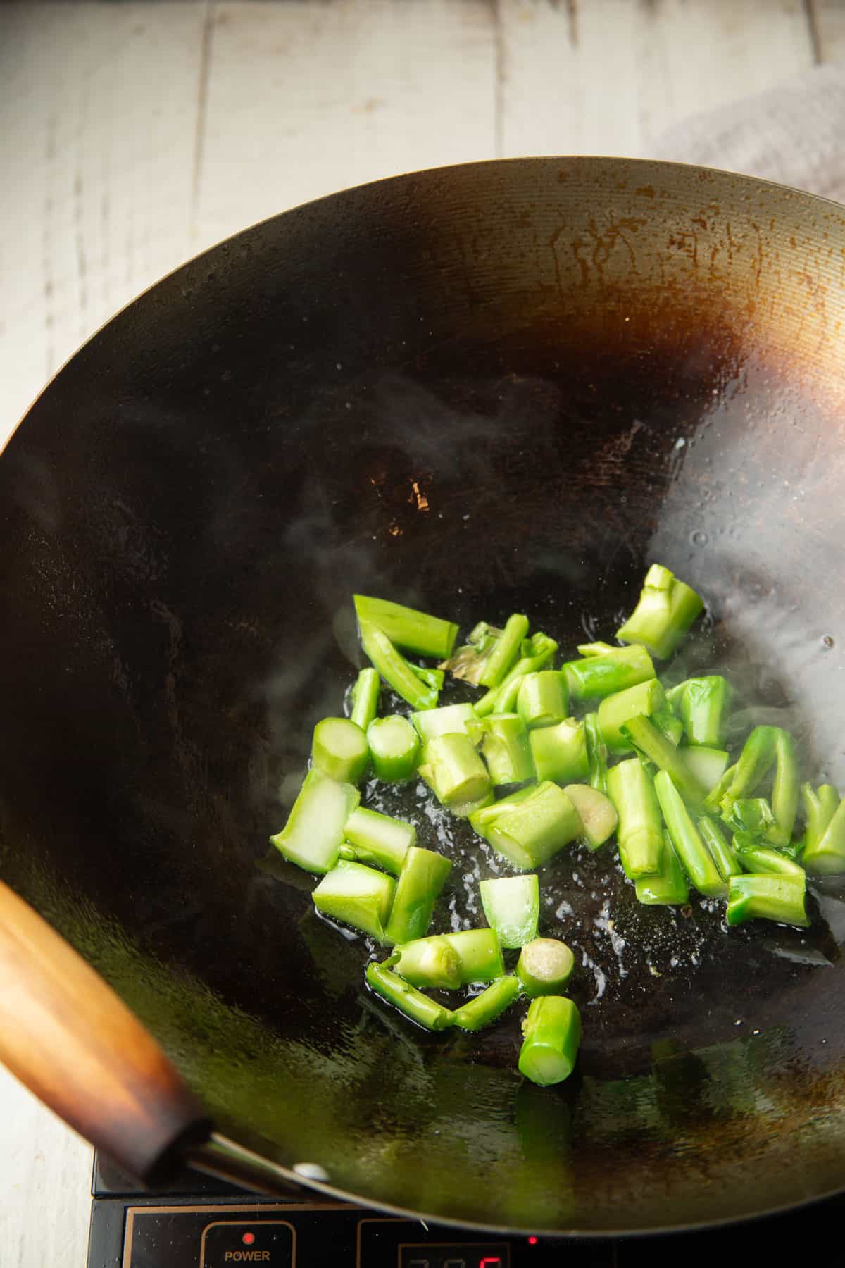 Chinese broccoli stems cooking in a wok.