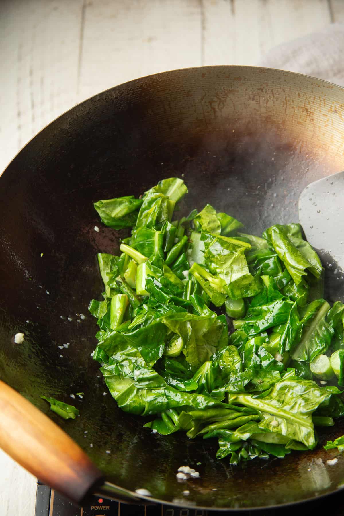 Chinese broccoli leaves and stems cooking in a wok.