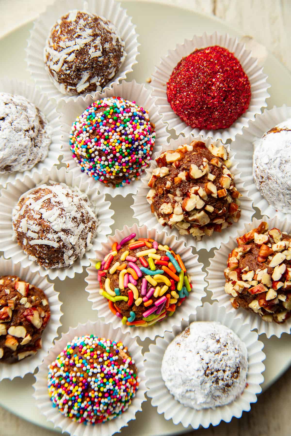 Vegan Rum Balls with various toppings on a white plate.