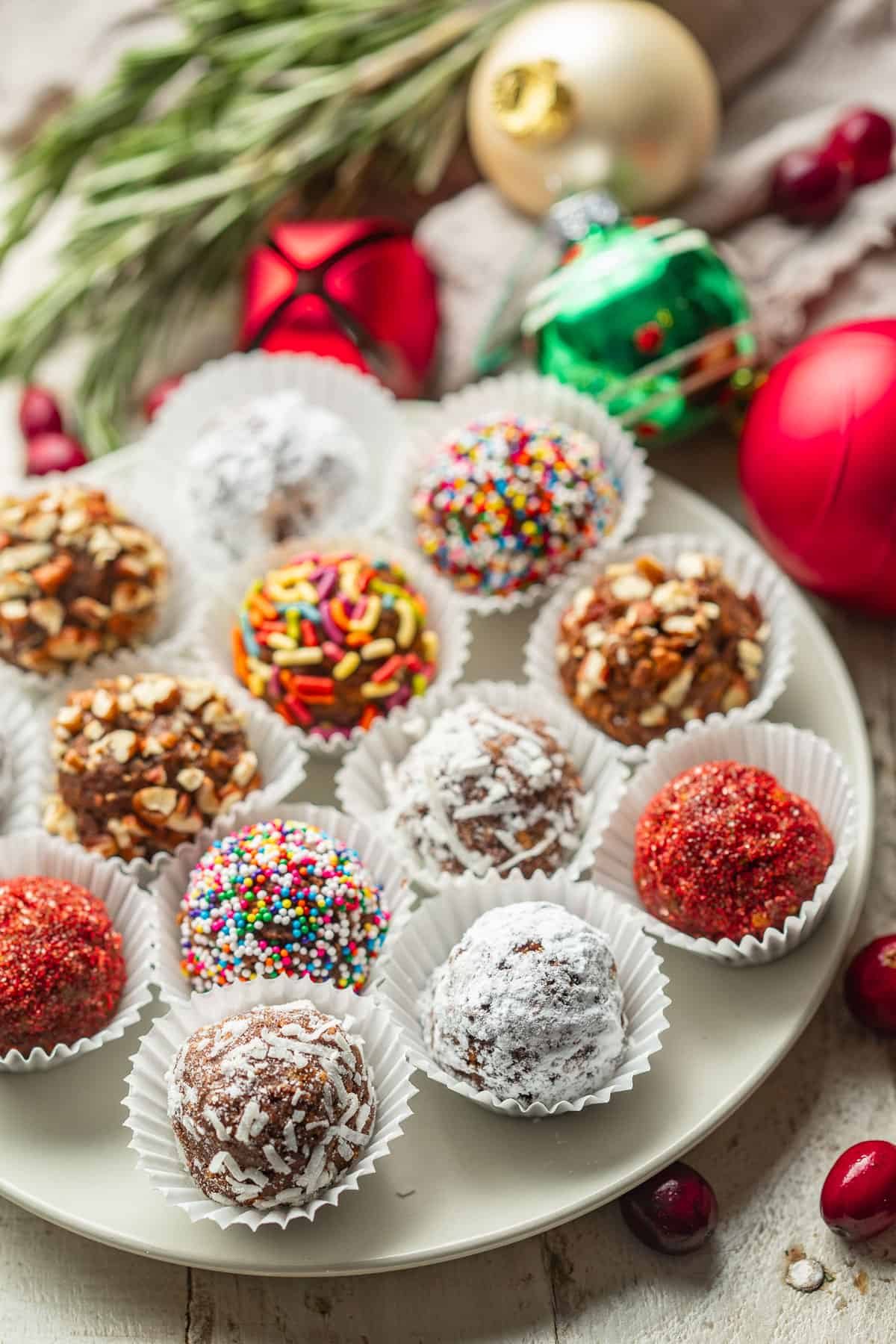 Plate of vegan rum balls with Christmas ornaments in the background.