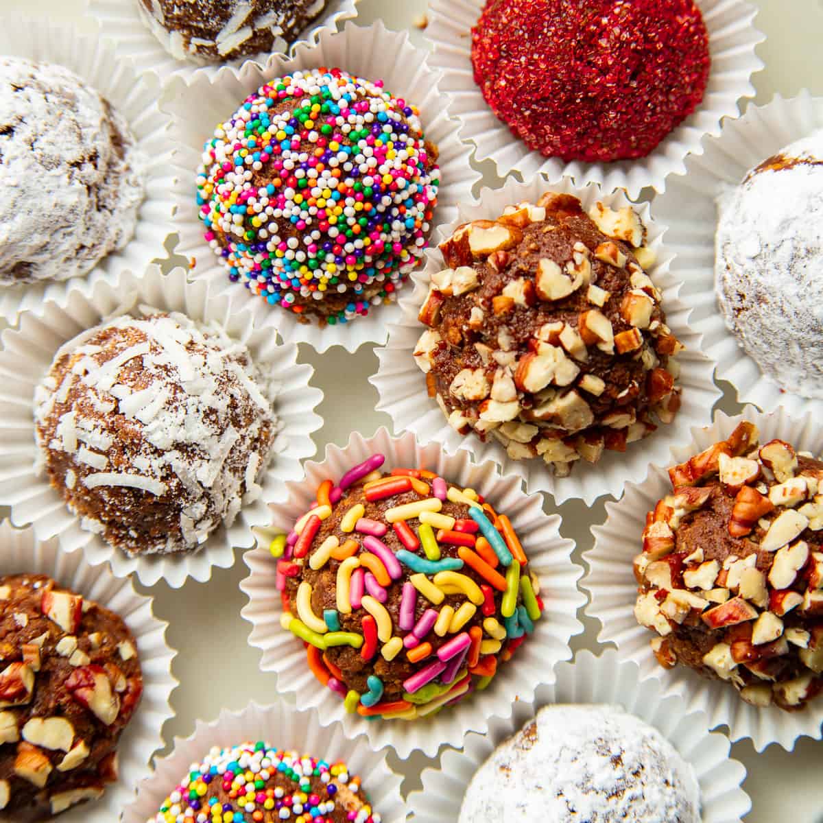 Vegan Rum Balls with various toppings on a white surface.