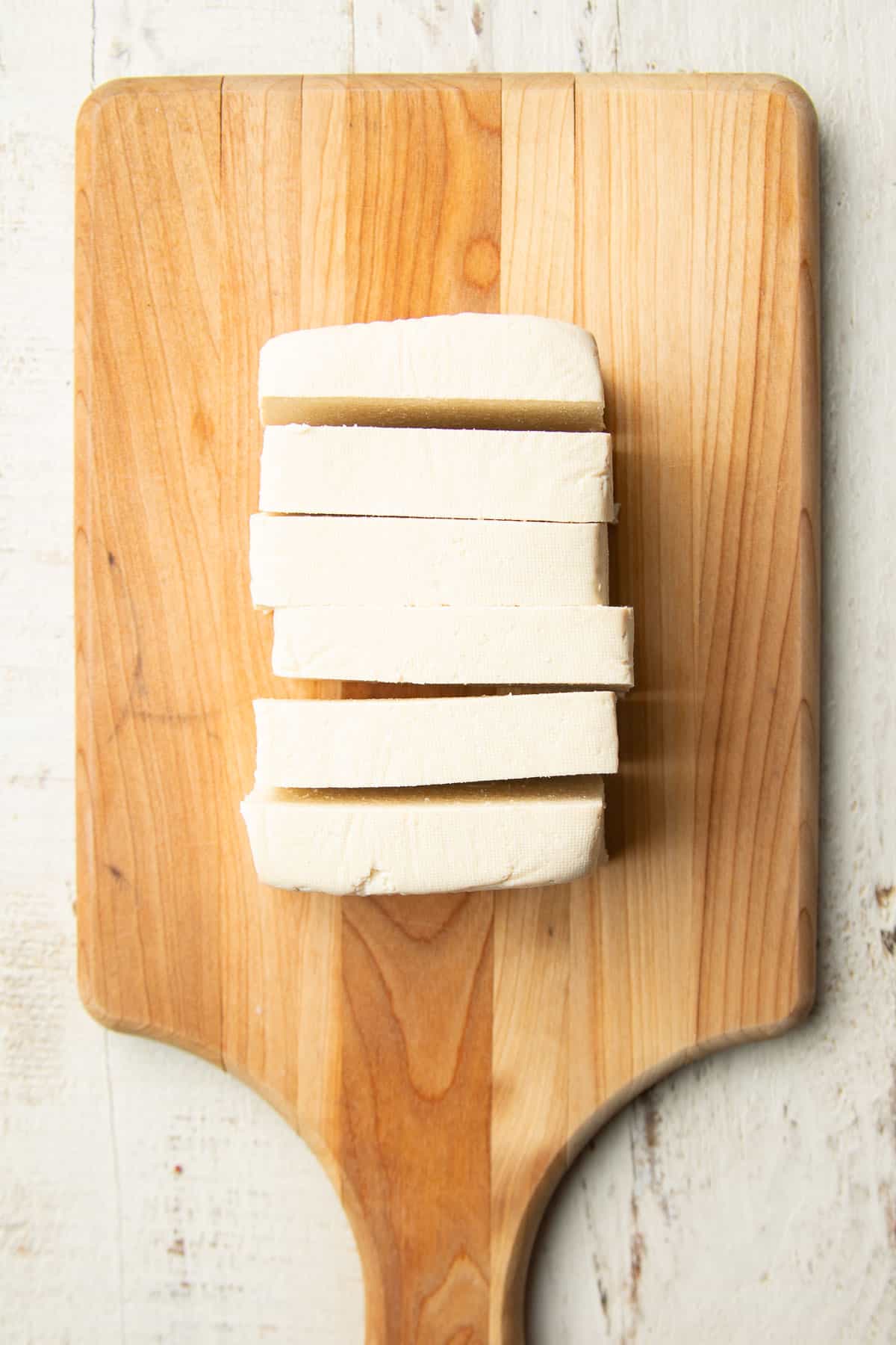 Sliced block of tofu on a wooden cutting board.