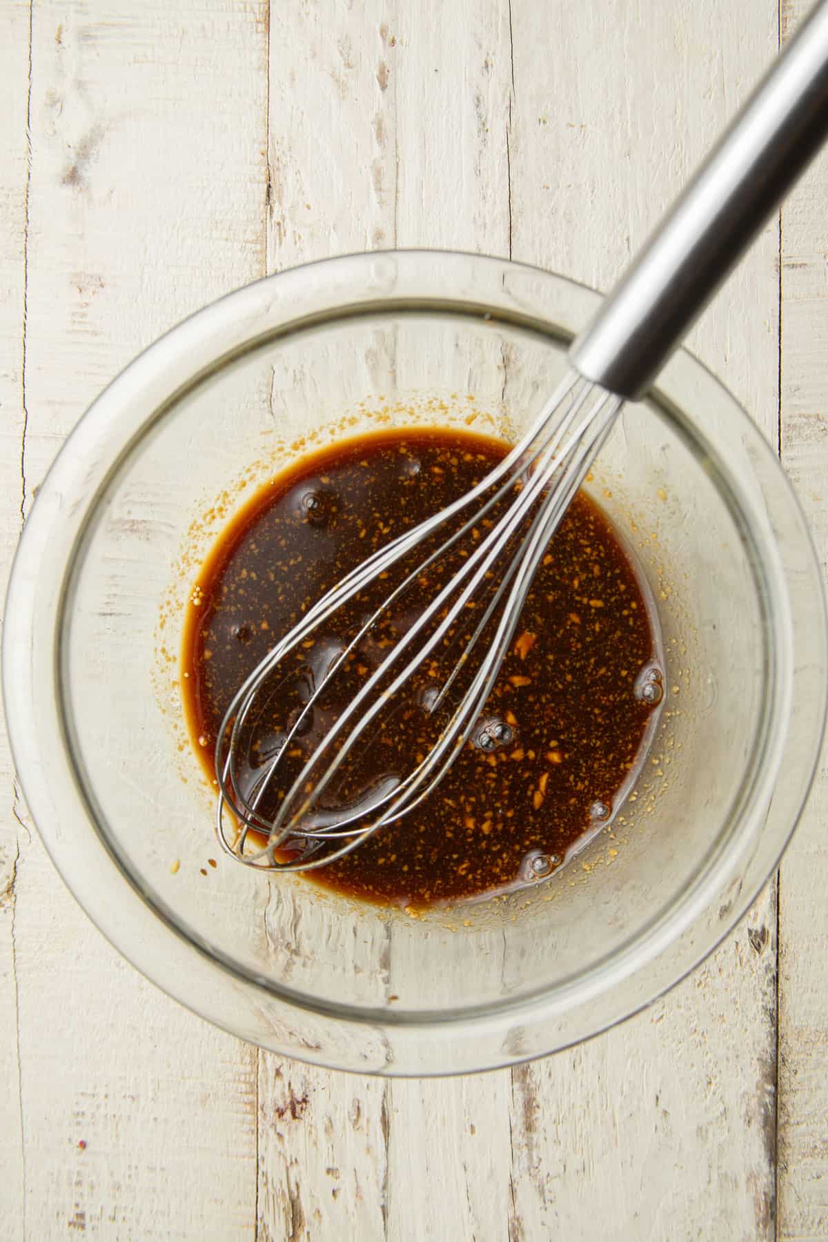 Balsamic sauce in a glass bowl with wire whisk.