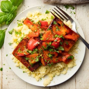 Balsamic Tofu Steaks with couscous and red bell peppers on a dish with a fork.