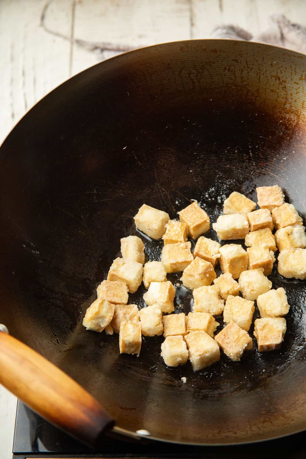 Fried tofu cubes in a wok.