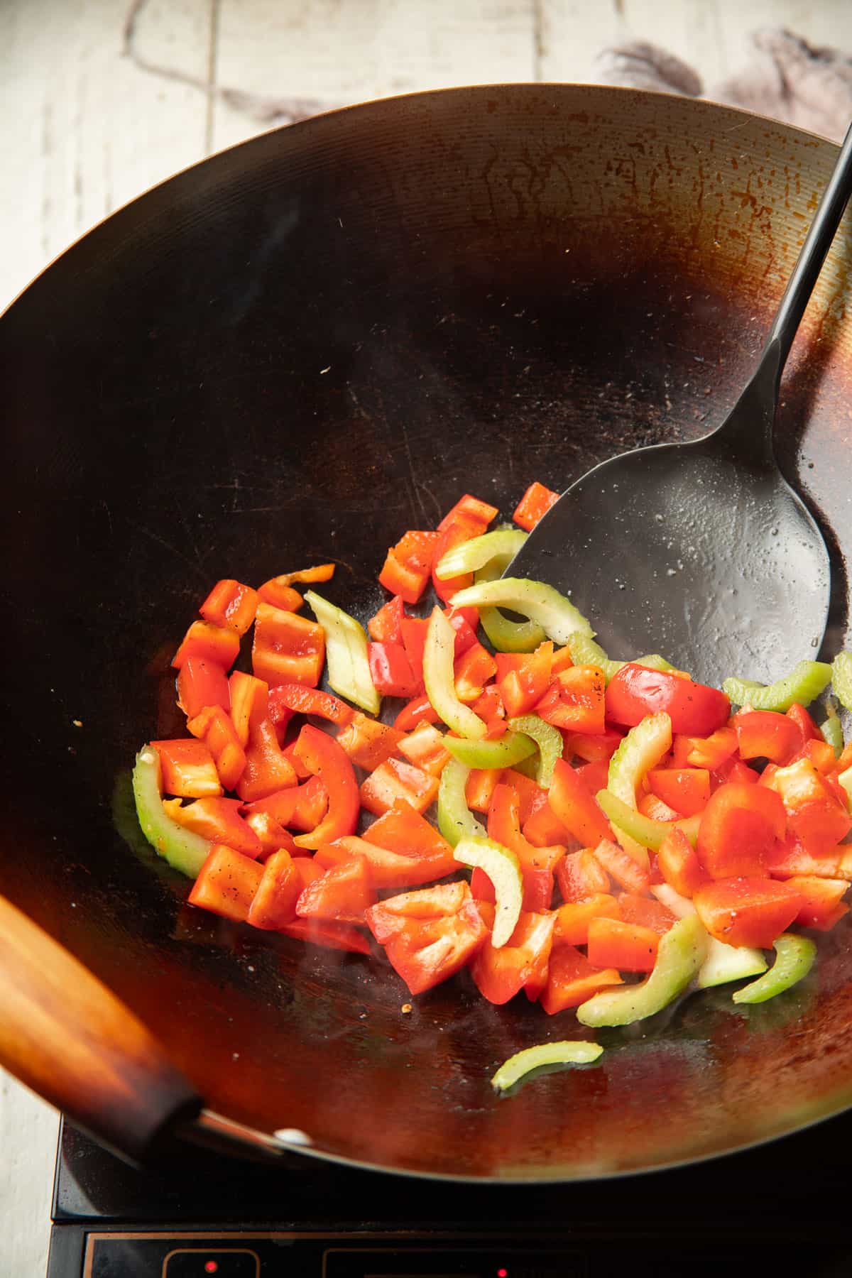 Red bell pepper and celery cooking in a wok.